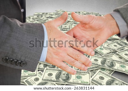 Two people going to shake their hands against pile of dollars