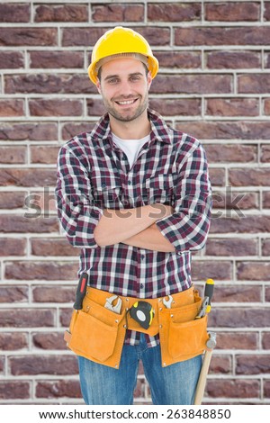 Confident male handyman wearing tool belt against red brick wall