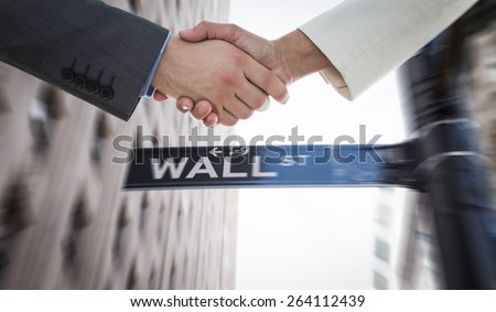 Shaking hands over eye glasses and diary after business meeting against wall street