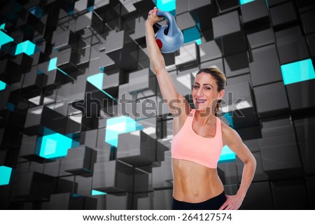 Female blonde crossfitter lifting kettlebell above head smiling at camera against blue and black tile design