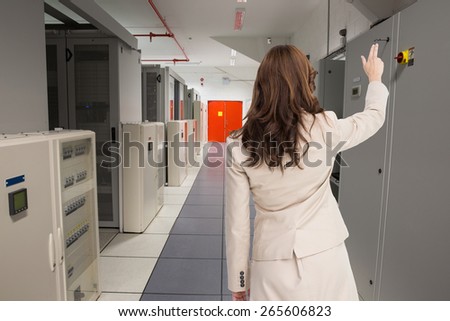 Brunette businesswoman standing back to camera against data center