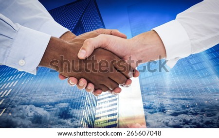 Close-up shot of a handshake in office against low angle view of skyscrapers at sunset