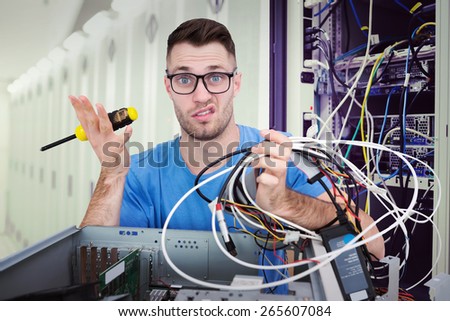 Portrait of confused it professional with screw driver and cables in front of open cpu against data center