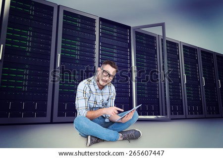 Handsome hipster using tablet pc against server towers