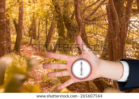 Hand with fingers spread out against tranquil autumn scene in forest