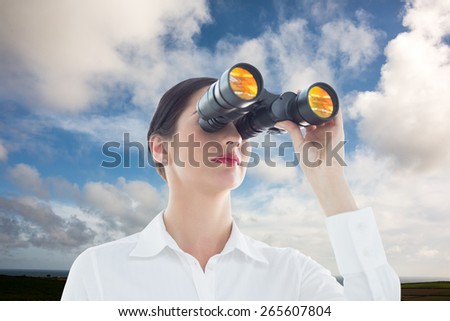 Business woman looking through binoculars against blue sky with white clouds