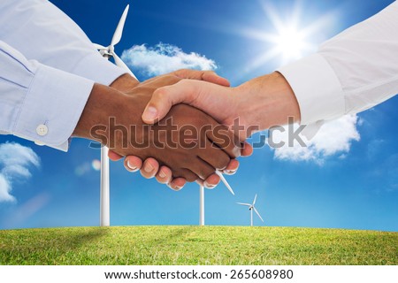 Close-up shot of a handshake in office against digital landscape with three wind turbines