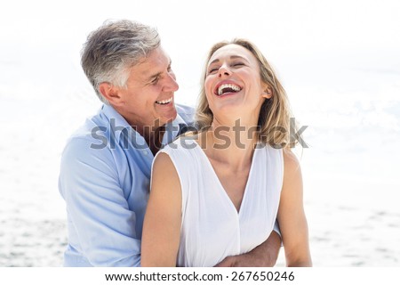 Happy couple laughing together at the beach