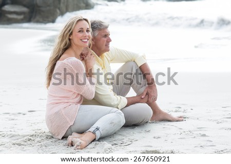 Happy couple sitting on the sand at the beach