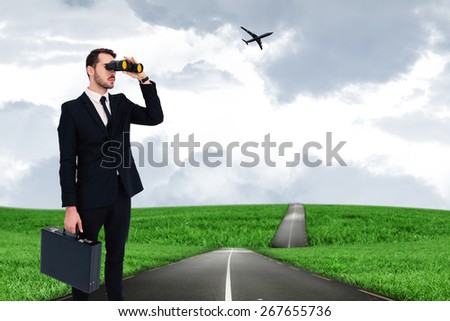 Businessman holding a briefcase while using binoculars against road leading out to the horizon