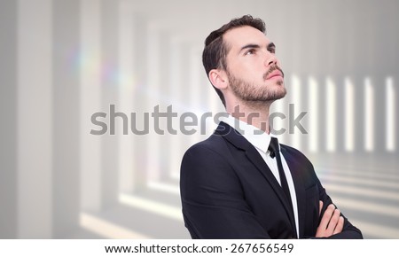 Thinking businessman with his arms crossed against curved white room