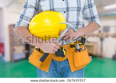 Technician holding hammer and hard hat against workshop
