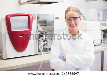 Smiling scientist looking at camera arms crossed in laboratory