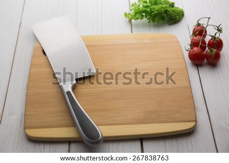 Chopping board with large knife and ingredients shot in studio