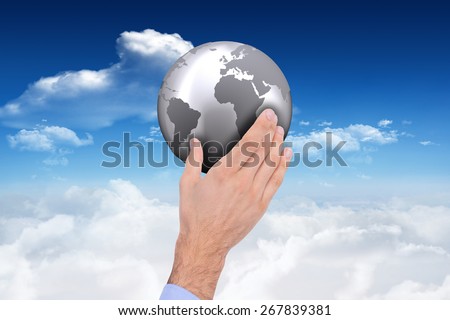 Businessman holding hand out in presentation against bright blue sky with clouds