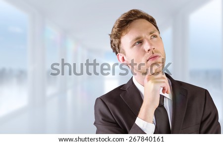 Young businessman thinking with hand on chin against bright white hall with windows