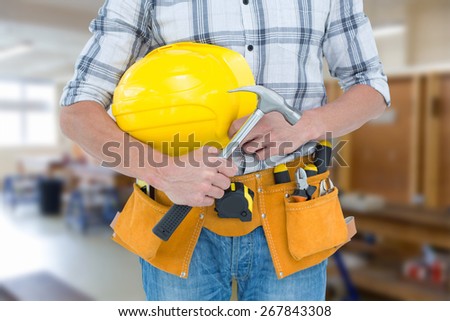 Technician holding hammer and hard hat against workshop