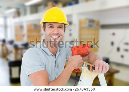 Happy technician holding drill machine while leaning on ladder against workshop