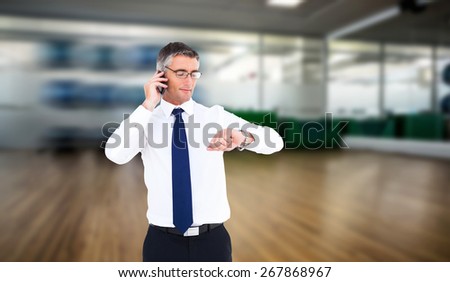 Businessman on the phone looking at his wrist watch against fitness studio