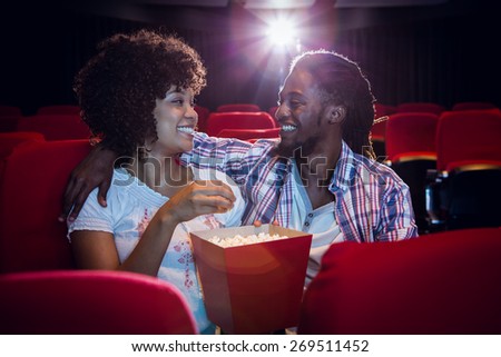 Happy young couple looking at each other at the cinema