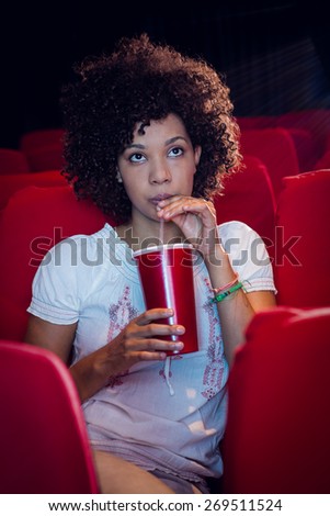 Young woman watching a film and drinking a soda at the cinema