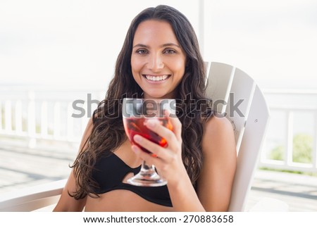 Pretty brunette sitting on a chair and drinking cocktail in patio