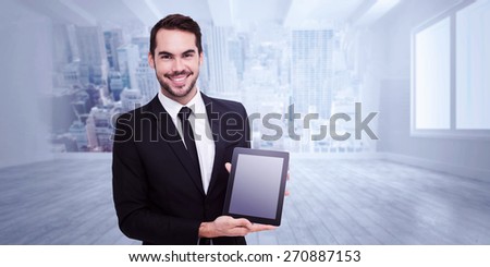 Smiling businessman showing his tablet pc against city scene in a room
