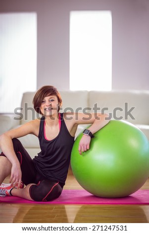 Fit woman sitting next to exercise ball at home in the living room
