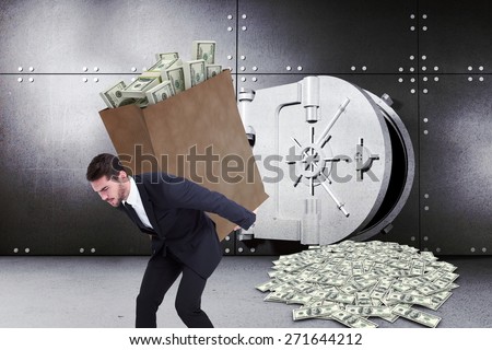 Businessman carrying bag of dollars against digitally generated opened safe