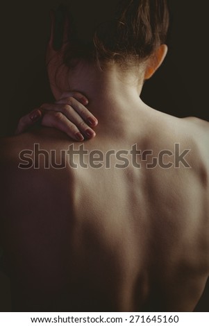 Nude woman with a shoulder injury on black background