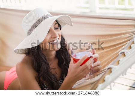 Pretty brunette relaxing on a hammock and using tablet pc in patio