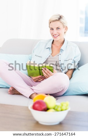 Pretty blonde woman reading a book on the couch in the living room