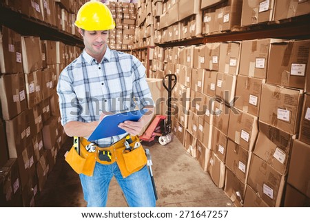 Architect writing notes on clip board against boxes in warehouse
