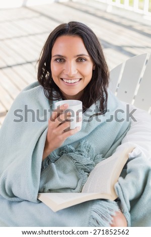 Pretty brunette sitting on a chair and drinking coffee in patio