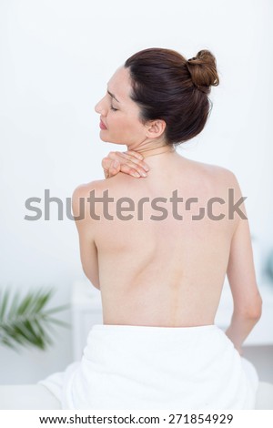 Woman touching her shoulder in medical office