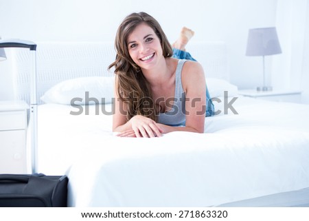 Happy woman with her case smiling at camera at home in the bedroom