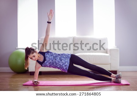Fit woman doing side plank at home in the living room