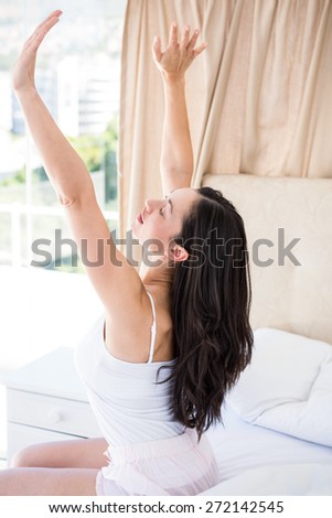 Pretty brunette stretching on bed at home