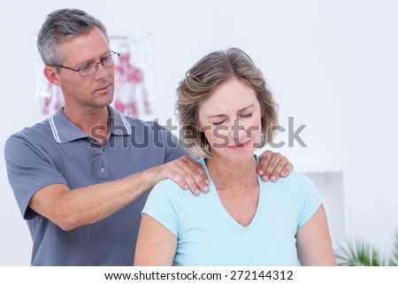 Doctor massaging his patient shoulders in medical office