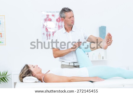 Doctor stretching his patients leg in medical office