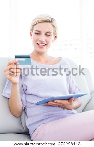 Pretty blonde woman doing online shopping in the living room