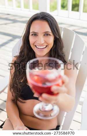 Pretty brunette sitting on a chair and drinking cocktail in patio