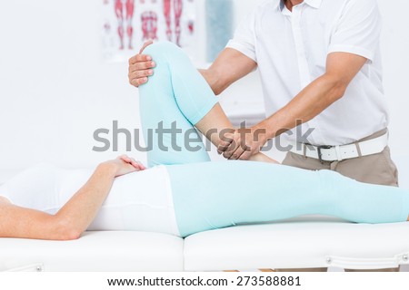 Doctor stretching his patients leg in medical office