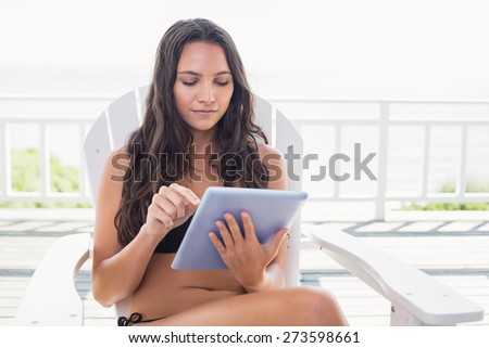 Pretty brunette sitting on a chair and using tablet pc in patio