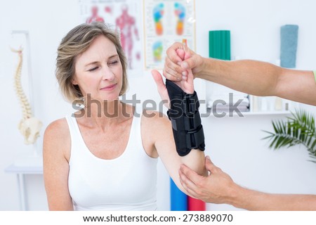 Doctor examining his patients wrist in medical office