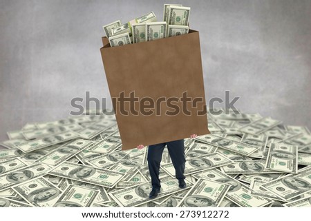 Businessman carrying bag of dollars against grey room