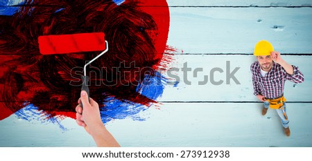 Handyman holding paint roller against painted blue wooden planks