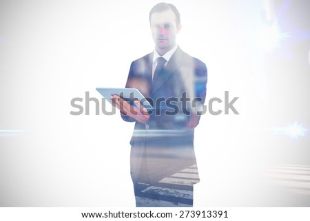 Serious charismatic businessman holding a tablet computer against blurred new york street