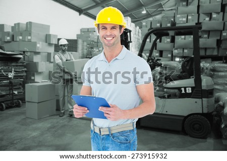 Happy architect holding clip board against warehouse worker loading up pallet