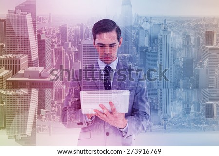Businessman holding a tablet computer against room with large window looking on city